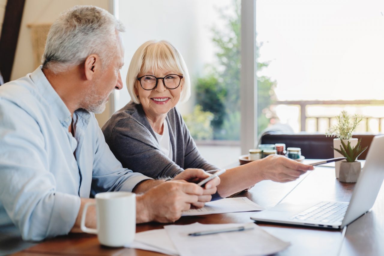 senior couple doing home finances using laptop indoors